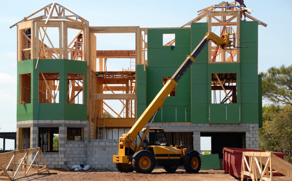 house in the middle of construction with machinery in front